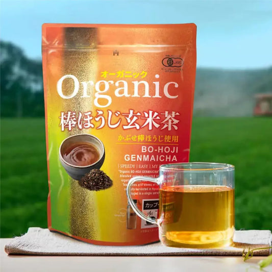 日本製九州產有機棒焙茶玄米茶 100 包裝，展現焙煎後的茶梗與金色炒米混合，散發出溫暖茶香之產品情境照。